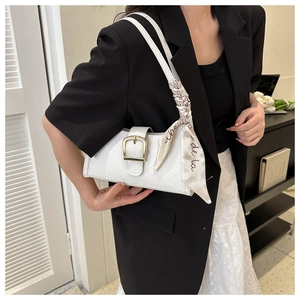 Detailed view of white baguette bag with V-quilted pattern and scarf wrapped handle