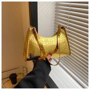Detail of golden crocodile embossed leather texture on a crescent baguette shoulder bag