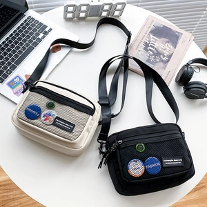 Close-up of casual canvas messenger bags in black and beige on a lifestyle desk setup
