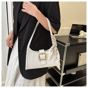 Detail of white quilted underarm bag with gold hardware and stylish printed silk scarf