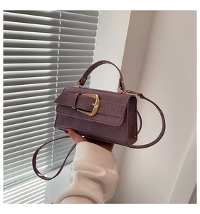 Détail du sac bandoulière violet texture crocodile avec boucle dorée décorative