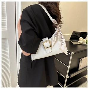 Detail of white quilted underarm bag with gold buckle and decorative silk scarf on strap