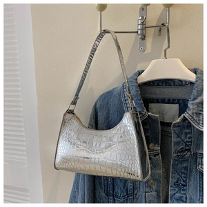 Detail of silver crocodile pattern texture on a glossy metallic faux leather baguette bag
