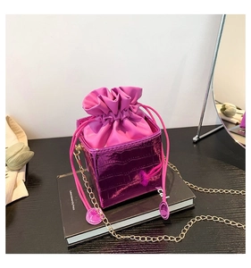 Dettaglio borsa a secchiello viola coccodrillo con coulisse rosa e tracolla a catena d'oro