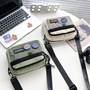 Detail of canvas messenger bags in beige and green colors with stylish mesh pockets