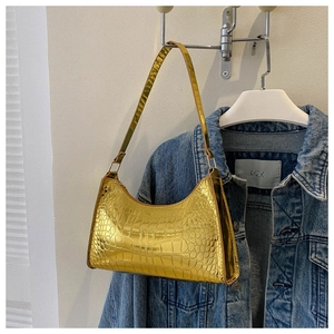 Close-up of golden faux leather baguette bag with shiny crocodile texture pattern