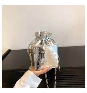 Dettaglio della trama a coccodrillo argento su mini borsa a secchiello con catena d'oro