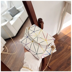 Macro view of geometric holographic pattern and golden chain on white crossbody bag