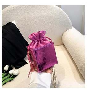 Dettaglio mini borsa a secchiello viola stampa coccodrillo con coulisse e catena d'oro