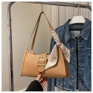 Detail of camel leather baguette bag with golden buckle and silk scarf decoration