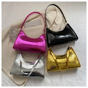 Detailed view of crocodile pattern handbags in pink, black, silver, and gold leather