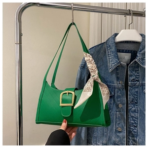 Close-up of green leather handbag featuring V-stitch quilting and a silk scarf accent
