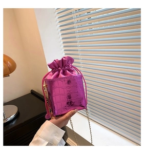Dettaglio borsa a secchiello fucsia con stampa coccodrillo, catena dorata e chiusura a coulisse