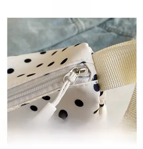 Detailopname van ritssluiting en zwarte stippen op witte nylon handtas voor dames