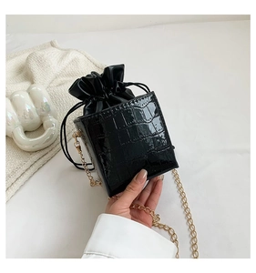 Dettaglio della texture in pelle a coccodrillo nera su borsa a secchiello strutturata