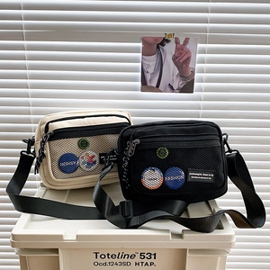 Detail showing two casual canvas crossbody bags in black and beige with front mesh pockets