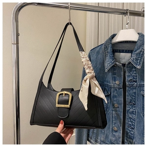 Detail of black quilted shoulder bag featuring gold hardware and elegant floral silk scarf