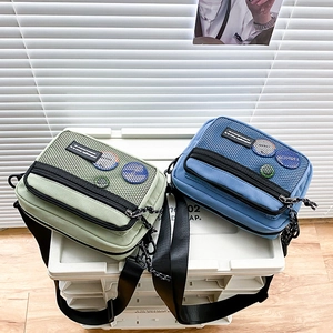 Detail view of canvas messenger bags in mint green and sky blue with mesh pockets