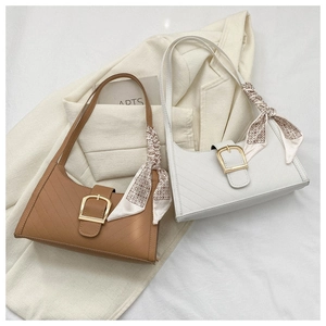 Detail view of brown and white shoulder bags with metallic buckles and silk scarves