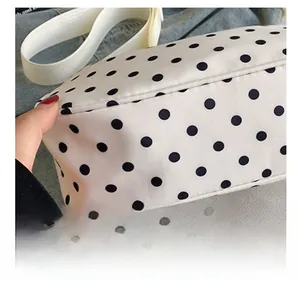 Detailopname van nauwkeurig stiksel op de witte nylon tas met stippen en brede riem
