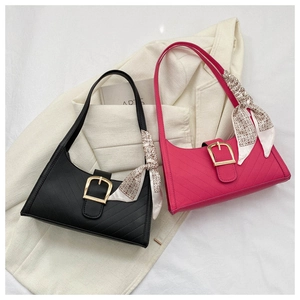 Detail of quilted leather bags with gold buckle and silk scarf on a beige blazer