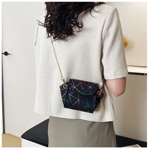 Detail view of black geometric laser crossbody bag with elegant gold chain strap on model