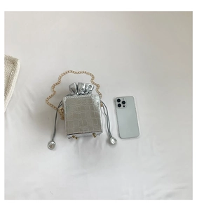 Dettaglio mini borsa a secchiello argento con motivo a coccodrillo, catena e chiusura a lacci