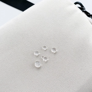 Close-up of water-resistant canvas fabric with clear water droplets and strap detail