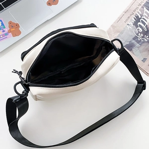 Detail view of canvas crossbody bag interior with black lining and zip compartment