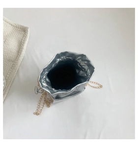 Dettaglio della borsa a secchiello argento con catena dorata e fodera nera