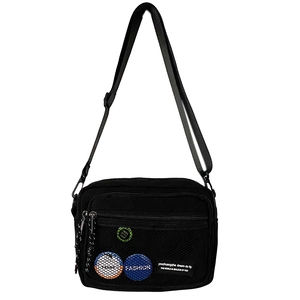 Detail of black canvas crossbody bag with mesh pocket and trendy fashion badges