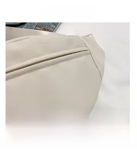 Close-up detail of reinforced stitching and invisible zipper on ivory nylon bag