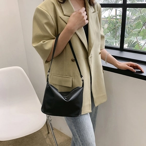 Minimalist black faux leather underarm shoulder bag for women shown with a blazer