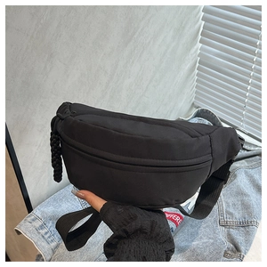 Detailed view of a black nylon waist bag with woven zipper pull held by a model