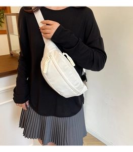 Detail of a white nylon chest bag with unique woven zipper and adjustable strap on model