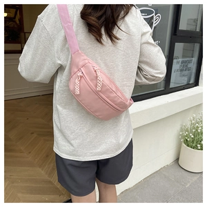 Detailed view of pink nylon chest bag with woven rope zipper pulls on adjustable strap