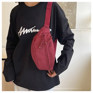Detailed side view of the wine red nylon crossbody chest bag with woven zipper puller