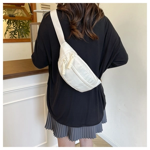 Rear view of model wearing a minimalist beige nylon crossbody chest bag with woven zippers