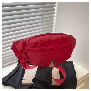 Close-up of red nylon waist bag featuring dual zipper closure and woven pull cords