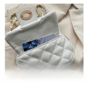Close-up of quilted white leather mini bag with gold lock and internal card slot detail