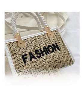 Détail du sac en paille avec attaches métalliques dorées et poignée tressée blanche