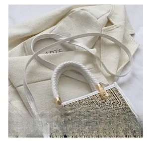 Détail du sac en paille tressée avec texte noir et bandoulière en PU blanc poli