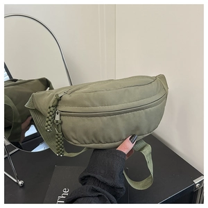 Detail of army green nylon chest bag featuring textured fabric and woven zipper pullers