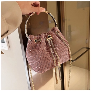 Macro shot of pink rhinestone bucket bag with gold circular handle and tassel drawstring