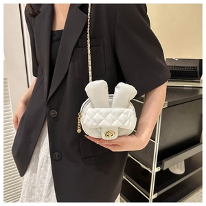 Detailed view of white quilted mini bag with bunny ears and gold twist lock on model