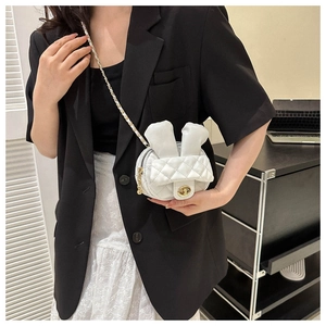 Detail view of mini white quilted crossbody bag with rabbit ears and gold chain strap