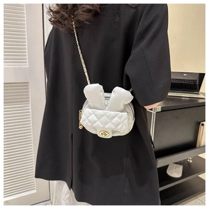 Detail of mini quilted rabbit ear crossbody bag with chain strap on a model back