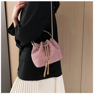 Pink rhinestone bucket bag with golden circular handle and tassel details shown on model