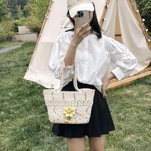 Fashionable beige woven tote bag with sunflower pendant in an outdoor camping scene