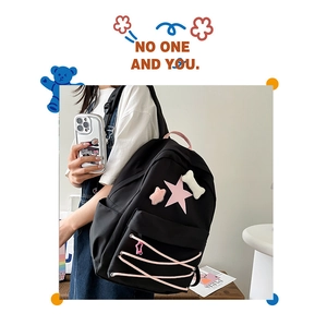Detail view of black canvas backpack with pink star patch and stylish lace-up design